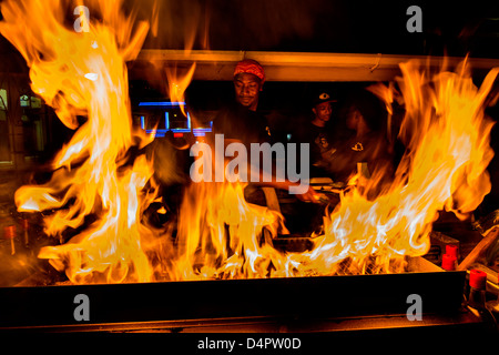 A man frying up fish on a BBQ at Oistins fish fry night, Oistins, parish of Christ Church, Barbados , Caribbean, West Indies Stock Photo