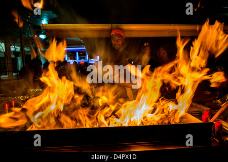 A man frying up fish on a BBQ at Oistins fish fry night, Oistins, parish of Christ Church, Barbados , Caribbean, West Indies Stock Photo