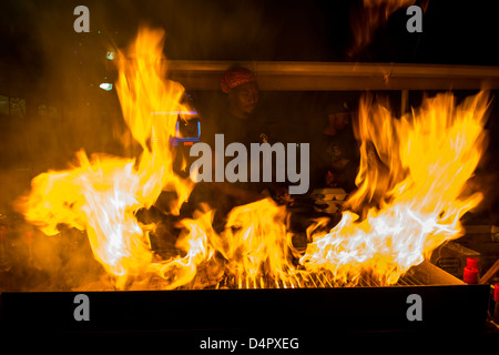 A man frying up fish on a BBQ at Oistins fish fry night, Oistins, parish of Christ Church, Barbados , Caribbean, West Indies Stock Photo