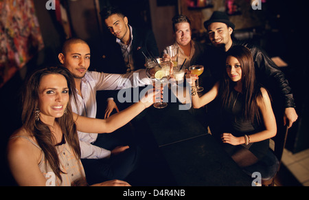 Group of friends at the bar raising their glass for a toast Stock Photo