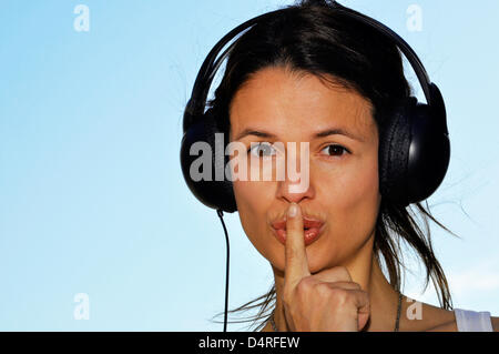 (dpa FILE) - An archive picture, dated 25 September 2011, shows an illustration of a young woman wear a headset while holding a finger to her mouth indicating to be quiet in Berlin, Germany. Fotoarchiv für Zeitgeschichte () Stock Photo