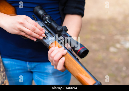 Young woman loading a hunting rifle with ammunition cartridge, Female 19 Caucasian Stock Photo