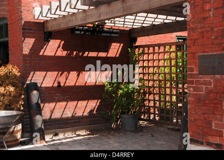 Sunshine streaming through an open roof throws rhomboid shadow patterns on a brick wall Stock Photo