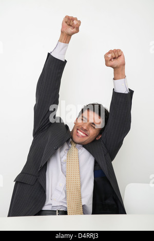 Mid-adult businessman raising arms in celebration Stock Photo