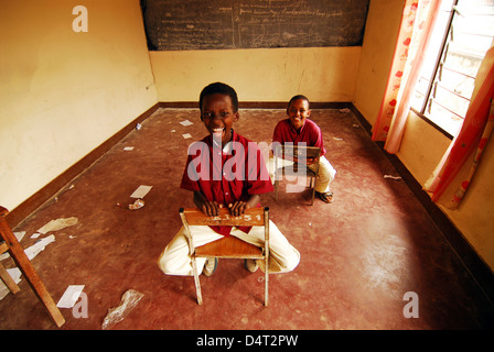 Burundi, Bujumbura, portrait of school boys sitting on chairs in a messy empty classroom. (MR) Stock Photo