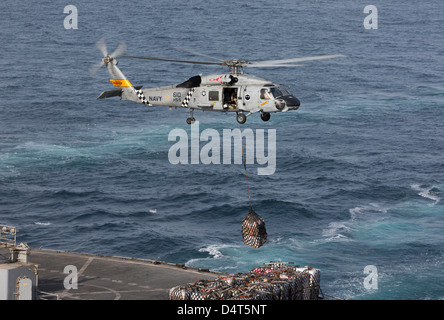 A SH-60J Seahawk conducts a vertical replenishment with USNS Supply. Stock Photo