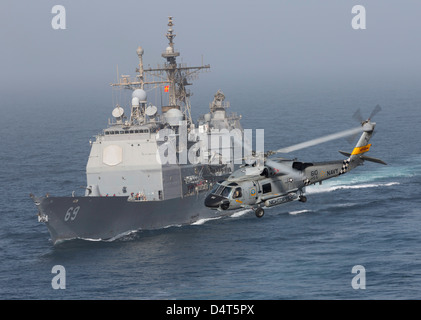 A SH-60J Seahawk flys by USS Vicksburg during a vertical replenishment. Stock Photo