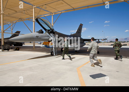 An alert crew scrambles to an F-16 to prepare it for takeoff Stock Photo