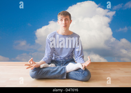 Teenager making funny face while sitting in lotus pose on the edge Stock Photo