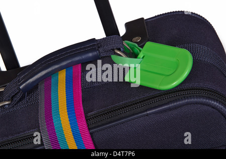 Closeup of bright green luggage tag and colorful belt on dark blue suitcase Stock Photo