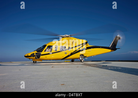 A Sikorsky S-76 utility helicopter prepares to take off from an oil rig. Stock Photo