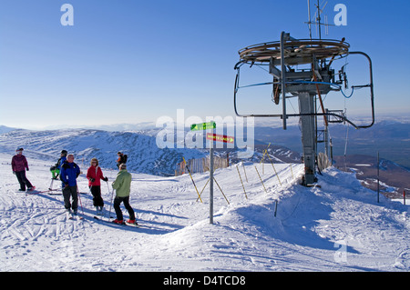 Group of skiers and snowboarders at top of M1 poma ski tow, Cairngorm mountain ski centre, Aviemore, Cairngorms National Park UK Stock Photo