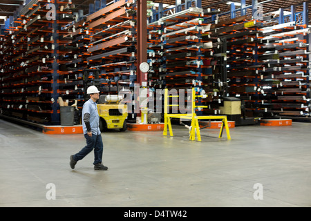 Worker walking in metal plant Stock Photo
