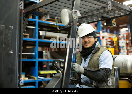 Worker driving forklift in metal plant Stock Photo
