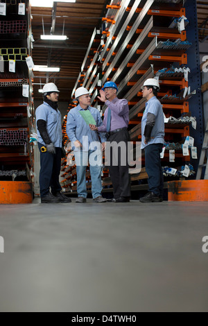 Workers and businessman in metal plant Stock Photo