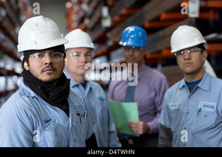 Workers and businessman in metal plant Stock Photo