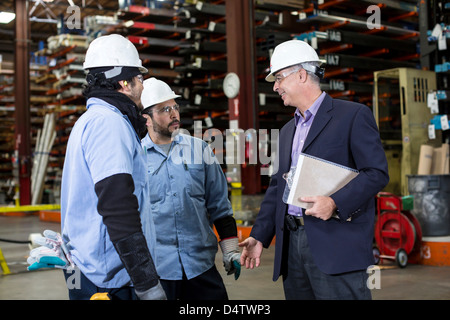 Workers and businessman in metal plant Stock Photo