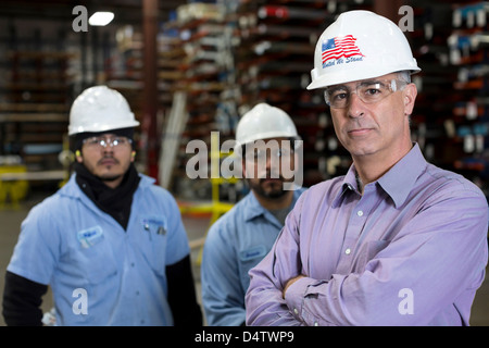 Workers and businessman in metal plant Stock Photo