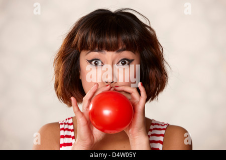 Woman blowing up balloon Stock Photo