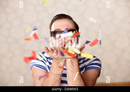 Man blowing confetti at party Stock Photo