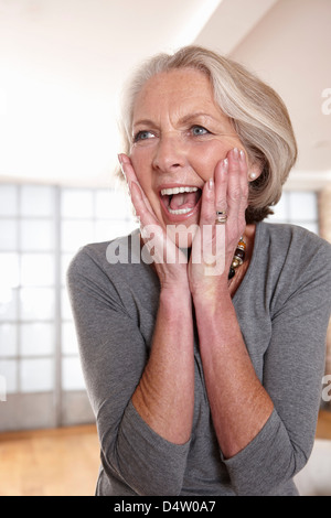 Smiling older woman gasping Stock Photo