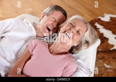 Older couple laughing on sofa Stock Photo