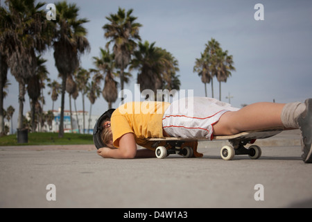 Boy laying on skateboard in park Stock Photo