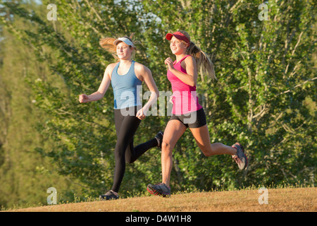 Teenage girls running together in field Stock Photo