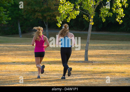 Teenage girls running together in field Stock Photo