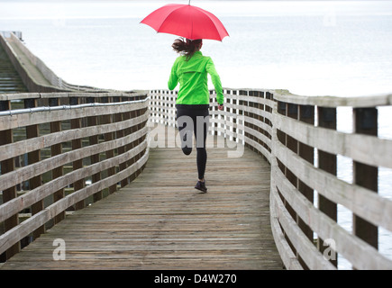 Woman running under umbrella Stock Photo