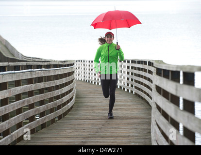 Woman running under umbrella Stock Photo