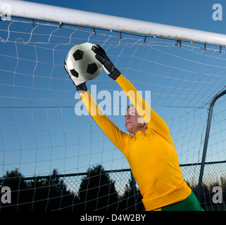 Soccer player catching ball in goal Stock Photo