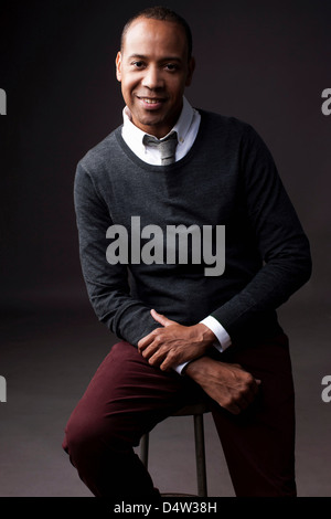 Smiling man sitting on stool Stock Photo
