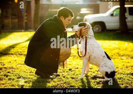 Man petting dog in park Stock Photo