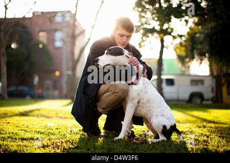 Man hugging dog in park Stock Photo