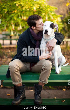 Man petting dog on park bench Stock Photo