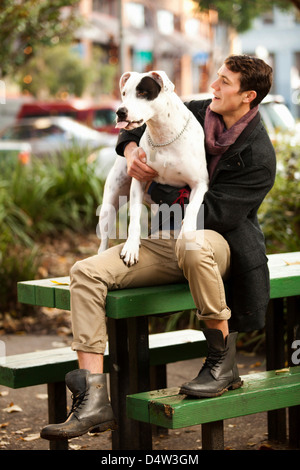 Man sitting with dog on picnic table Stock Photo