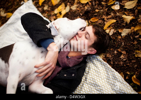 Man and dog hugging on picnic blanket Stock Photo