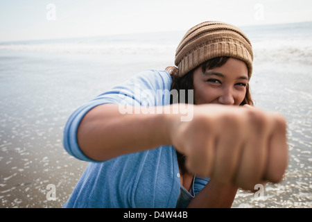 Smiling woman making fists on beach Stock Photo