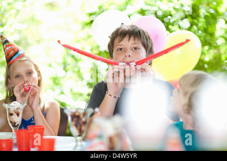 Children blowing noisemakers at party Stock Photo
