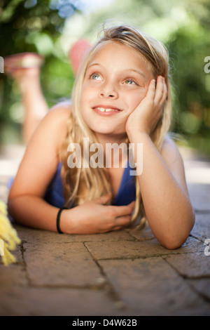 Girl laying on ground outdoors Stock Photo