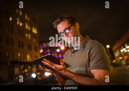 Man using tablet computer on city street Stock Photo