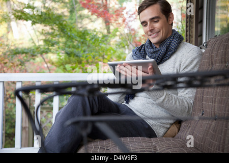 Man using tablet computer on porch Stock Photo