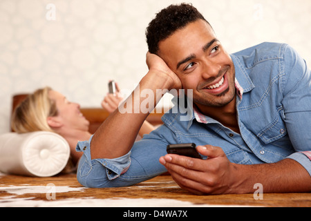 Smiling man using cell phone indoors Stock Photo