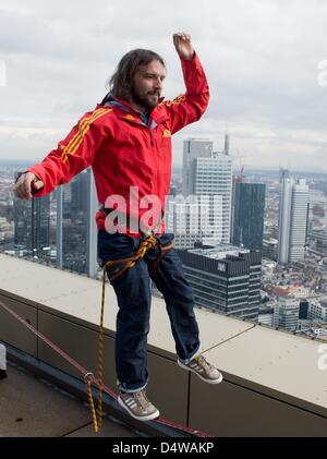 Frankfurt, Germany. 19th March 2013. Austrian 'slackliner' Reinhard Kleindl presents his skills on a roof of the tower 185 against the backdrop of the skyline of Frankfurt Main. Kleindl intends to walk across a slackline erected between the two towers of tower 185 at the Skyscraper Festival 2013. Photo: BORIS ROESSLER/dpa/Alamy Live News Stock Photo