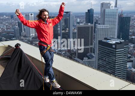 Frankfurt, Germany. 19th March 2013. Austrian 'slackliner' Reinhard Kleindl presents his skills on a roof of the tower 185 against the backdrop of the skyline of Frankfurt Main. Kleindl intends to walk across a slackline erected between the two towers of tower 185 at the Skyscraper Festival 2013. Photo: BORIS ROESSLER/dpa/Alamy Live News Stock Photo