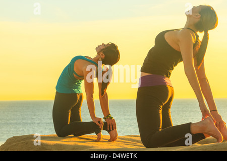 Women practicing yoga on rock formation Stock Photo