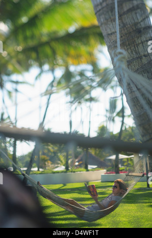 Man in hammock under palm trees Stock Photo