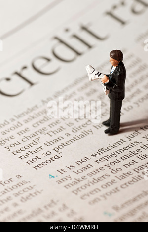 Close up of toy tiny small figure of a man businessman male person stood on financial page of newspaper business finance concept Stock Photo