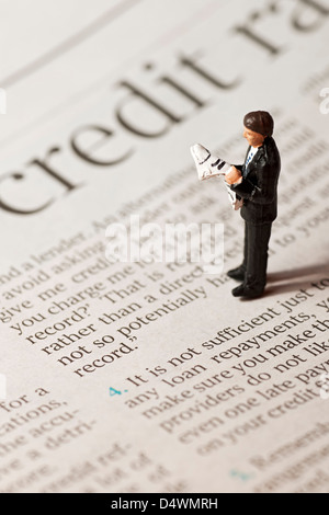 Close up of Toy tiny small figure of a man stood on financial page of newspaper business finance concept